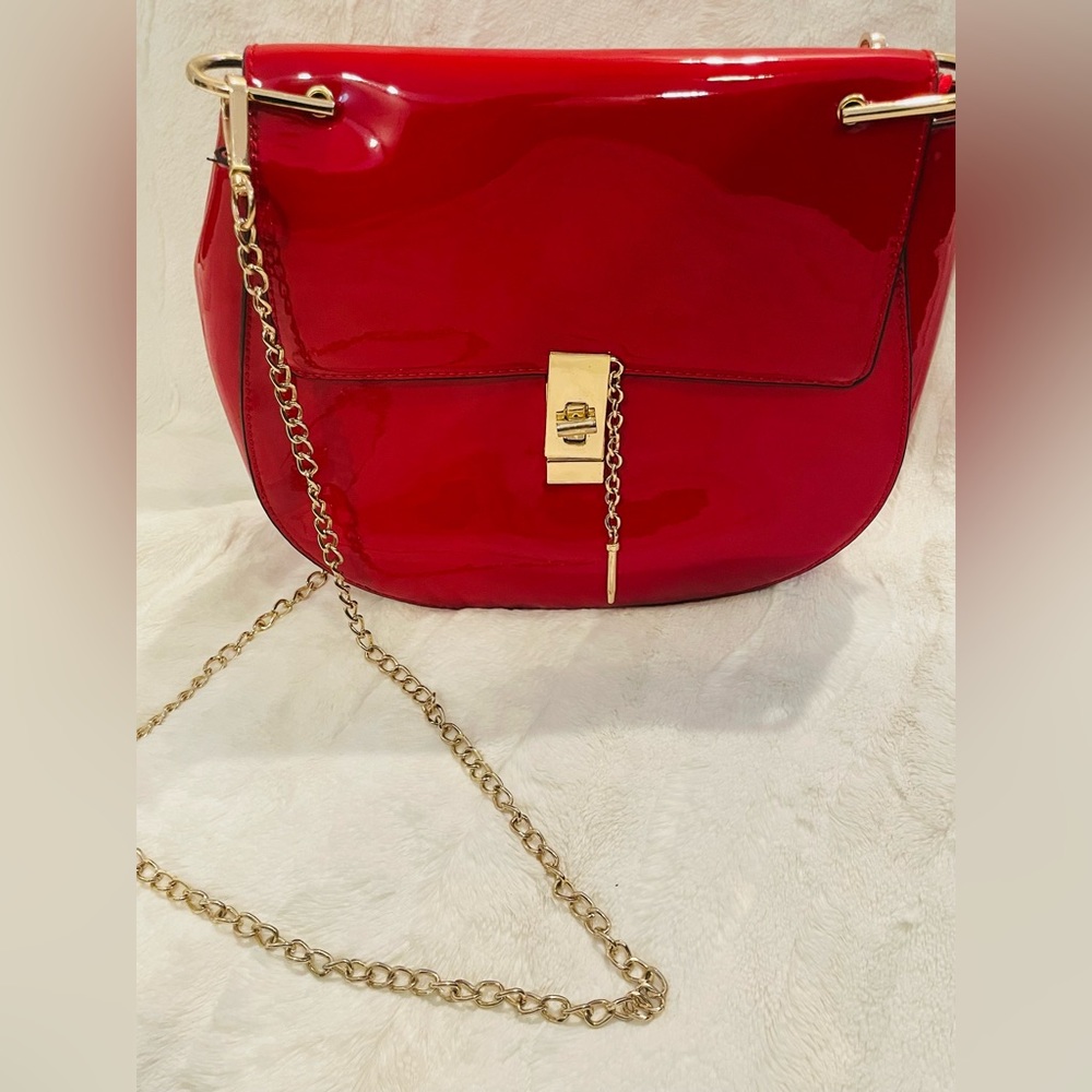 Red patent leather cross body with gold chain and lock detail. Med size